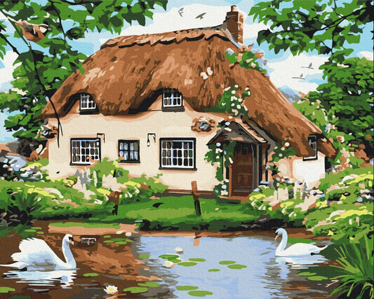 Reetdachhaus am Teich mit zwei Schwänen und Seerosen