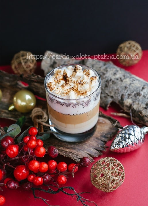 Geschichteter Latte mit gerösteten Marshmallows zwischen Weihnachtsbeeren und Kugeln