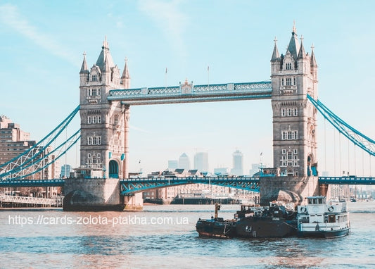 Zwillingstürme der Tower Bridge über der Themse, ein Boot fährt darunter hindurch, Skyline Londons im Hintergrund.
