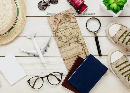 Flatlay mit Reiseutensilien: alte Karte, Pässe, Lupe, Spielzeugflugzeug, Strohhut