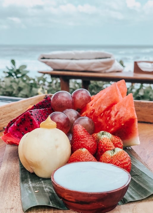Tropische Früchte mit Kokoscreme auf einem Strandtisch am Meer