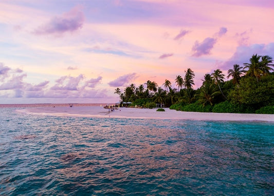 Rosa Sonnenuntergang über türkisfarbener Lagune und Palmenstrand