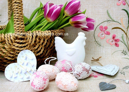 Wicker basket with tulips, a ceramic hen figurine and lace-wrapped pink Easter eggs