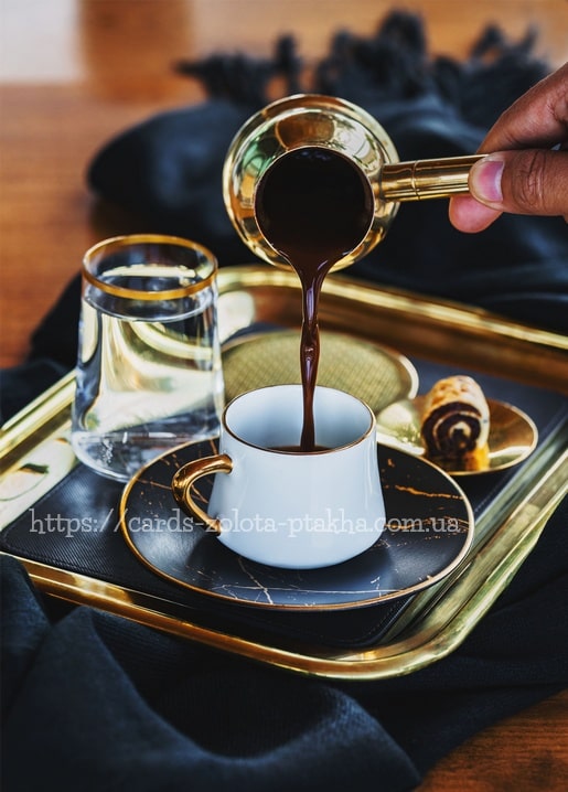 Türkischer Kaffee fließt aus einer Kupferkanne in eine golden umrandete Tasse