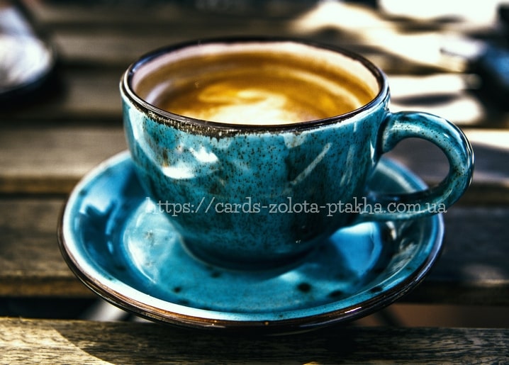 Chipped turquoise ceramic cup and saucer with coffee on a weathered wooden table