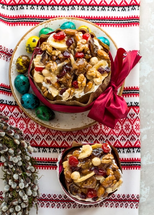 Ukrainische Paska mit Nüssen und Trockenfrüchten neben türkisfarbenen Wachteleiern und Rushnyk