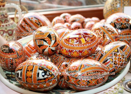 Pile of hand-painted Ukrainian pysanky eggs with orange, black and white geometric patterns