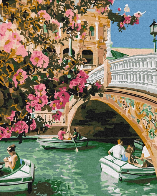Pink bougainvillea over a stone bridge with rowboats on a Venice canal