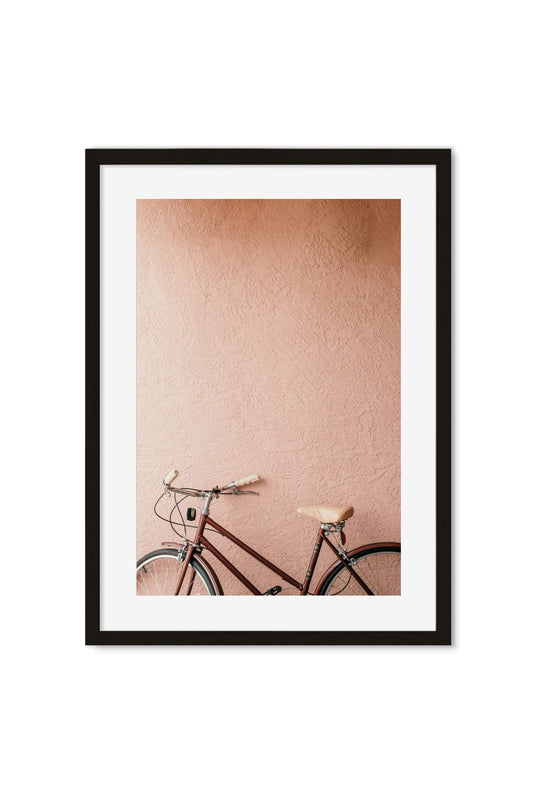 Vintage bicycle leaning against a sun-lit pink stucco wall