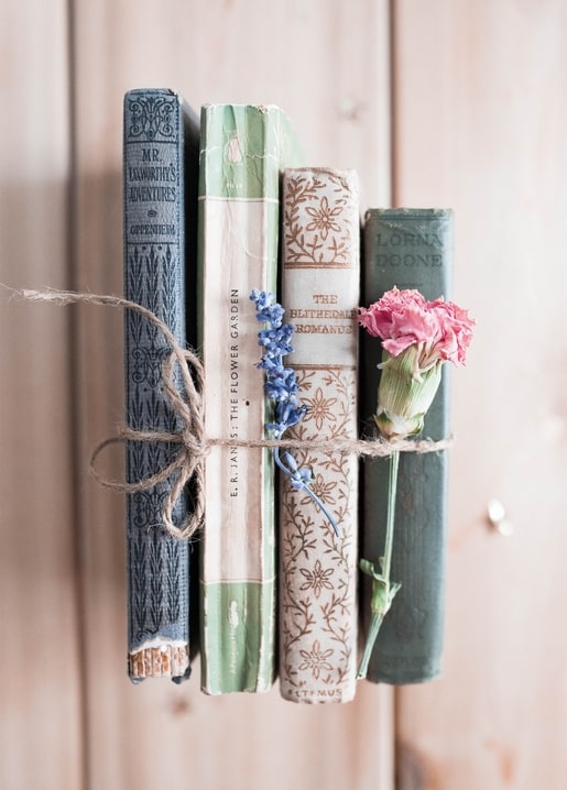 Bündel alter Bücher mit Kordel, getrocknetem Lavendel und einer rosa Nelke
