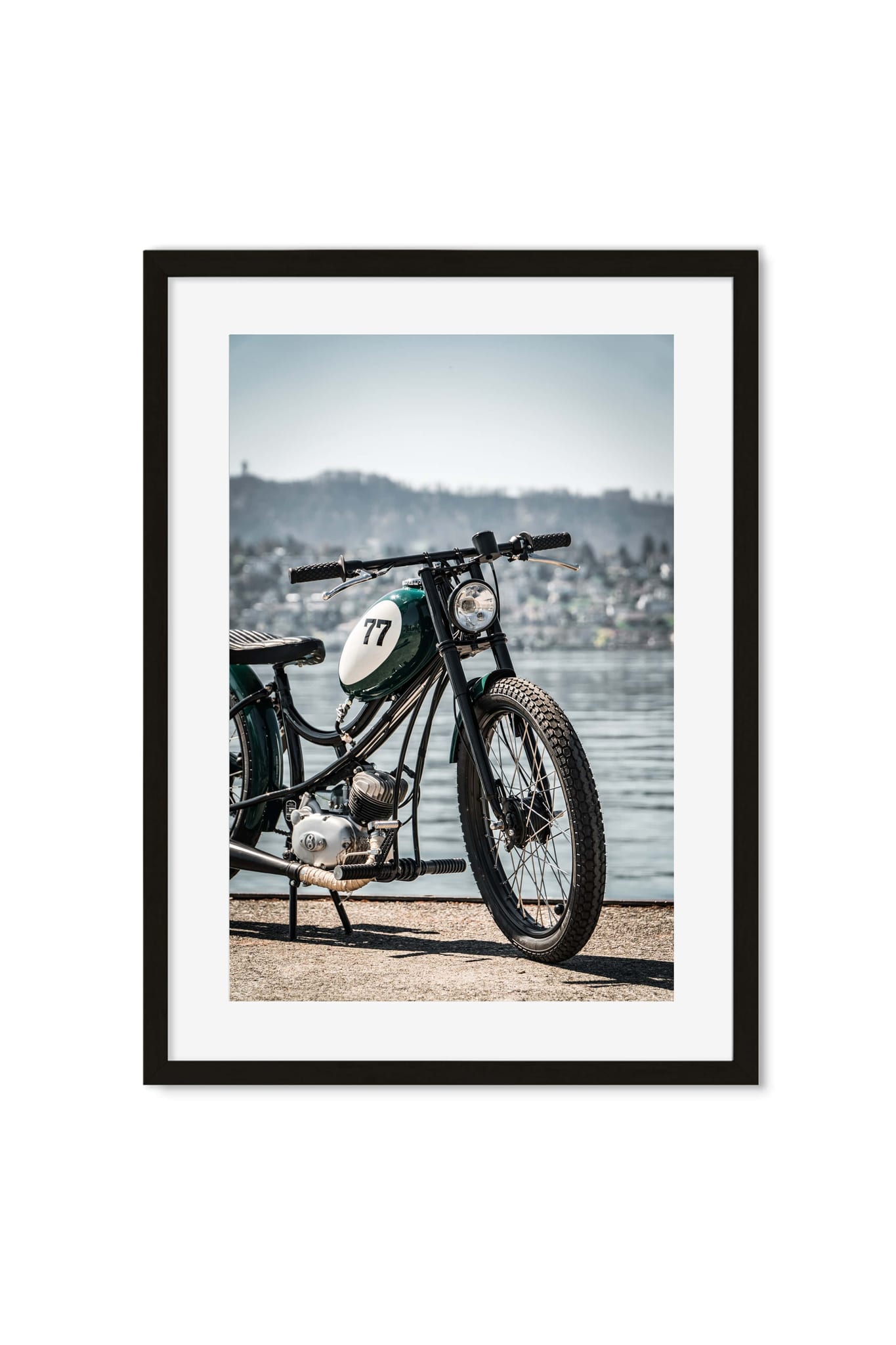 Vintage green cafe racer motorcycle numbered 77 parked by a lake