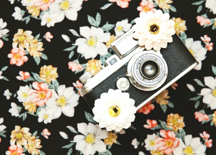 Vintage-Kamera mit weißen Blüten auf geblümtem Stoff