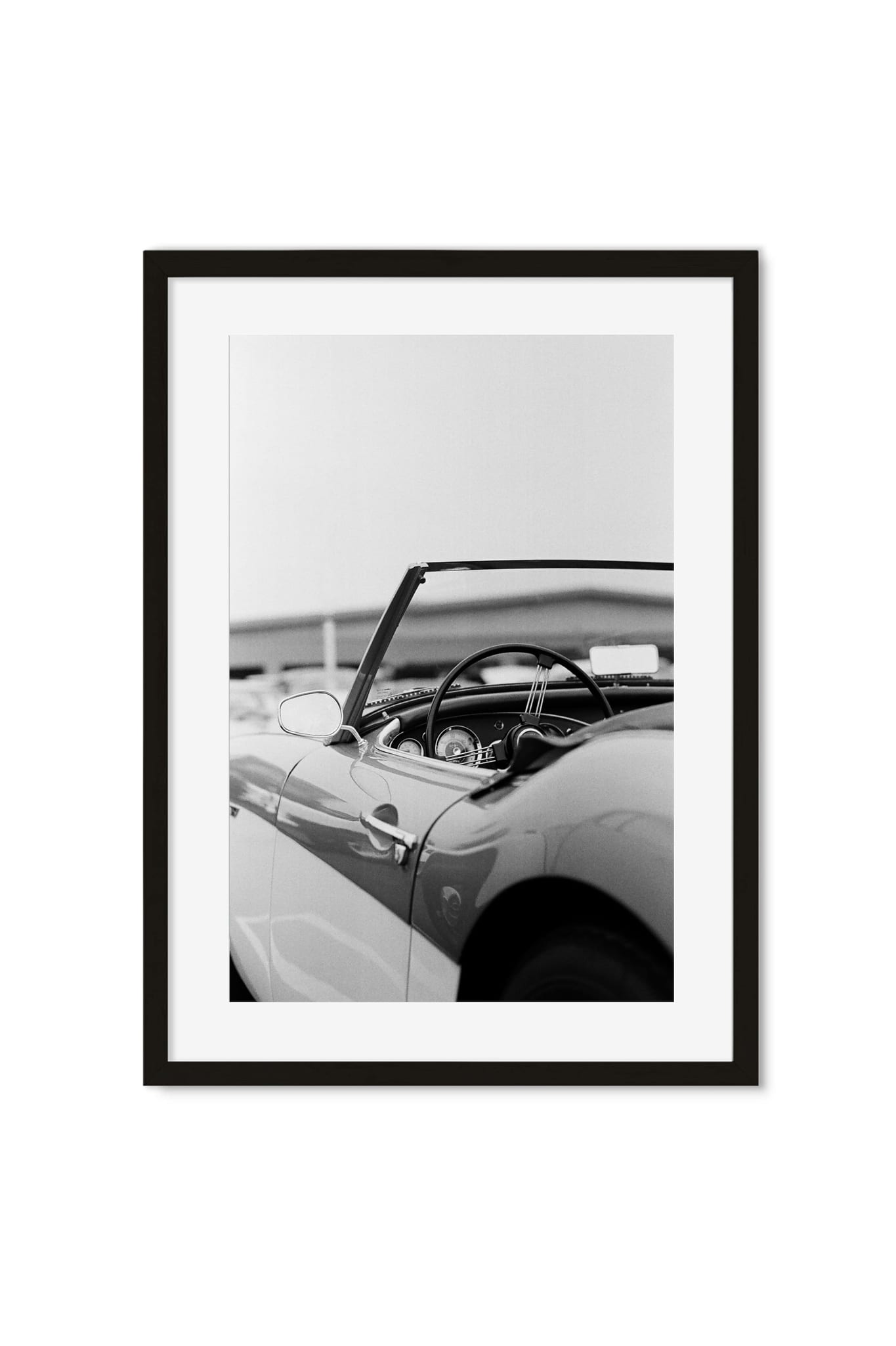 Black-and-white photo poster of a vintage convertible's steering wheel and folded soft top