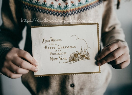 Goldgeprägte Vintage-Weihnachtskarte mit Häuschen-Motiv, in zwei Händen gehalten