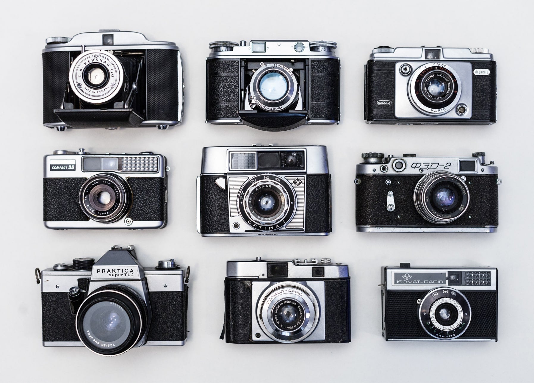 Flach liegende Anordnung von neun Vintage-Kameras, darunter eine Praktica und eine sowjetische FED-2