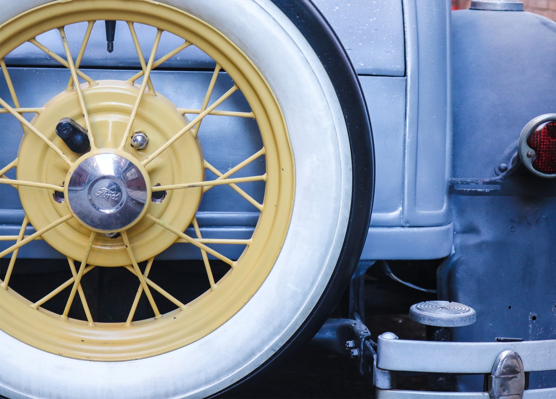 Nahaufnahme eines gelben Speichenrads eines Vintage-Ford mit Weißwandreifen und Chromradkappe