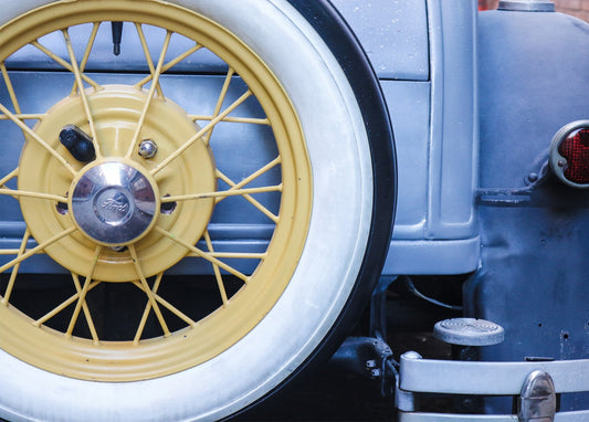 Nahaufnahme eines gelben Speichenrads eines Vintage-Ford mit Weißwandreifen und Chromradkappe