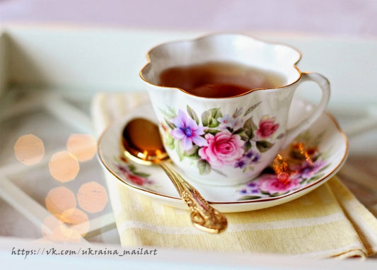 Vintage-Teetasse mit Tee, goldenem Löffel und Zuckerwürfeln vor warmem Bokeh-Licht