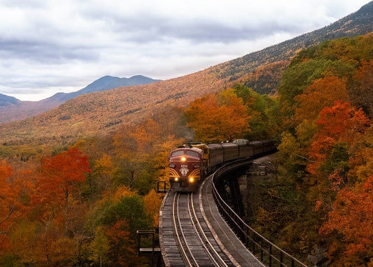 Vintage train crossing a mountain trestle bridge amid autumn foliage