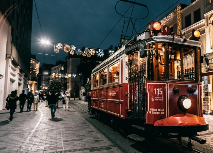 Red vintage tram on a festive city street decorated with lights at night