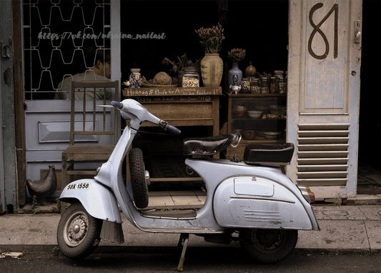 Blassblauer Vintage-Vespa-Roller parkt vor einem Laden mit der Nummer 81
