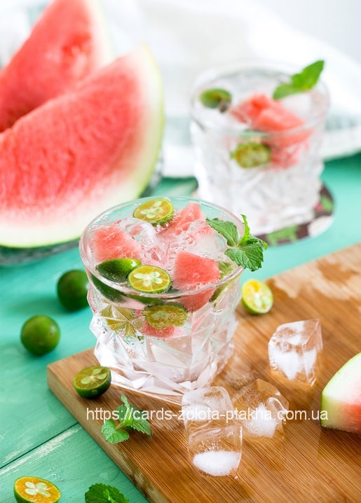 Watermelon mint cooler with lime and ice cubes on a turquoise wooden board
