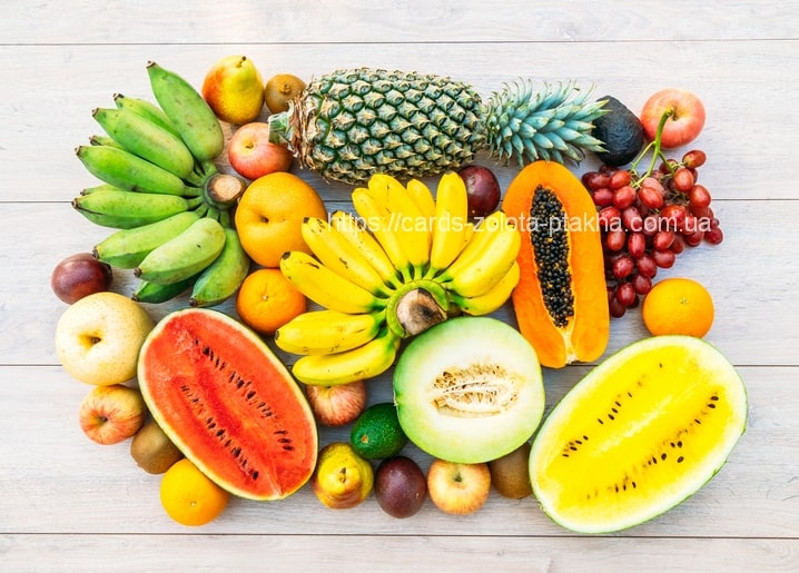 Sommerliches Fruchtarrangement mit Wassermelone, Ananas, Bananen, Papaya und Trauben auf Holztisch
