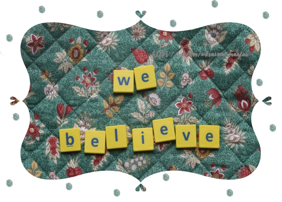 Gelbe Buchstabensteine mit dem Schriftzug We Believe auf blumengemustertem Stoff