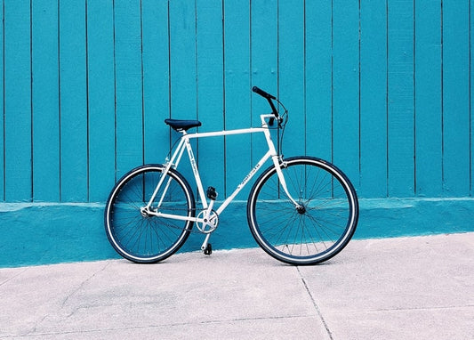 Weißes Fahrrad lehnt an einer leuchtend türkisen Holzwand