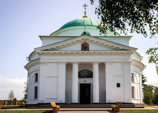 Біла церква в стилі ампір із зеленим куполом і колонадою в Диканці