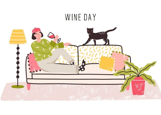 A woman in a pink beret sips wine on a patterned sofa while a black cat walks along the backrest, near a striped floor lamp.