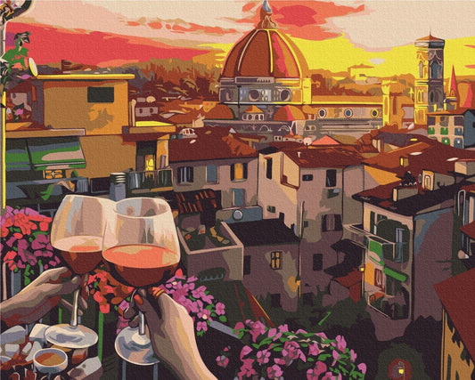Two hands toasting wine glasses on a balcony overlooking Florence's Duomo at sunset