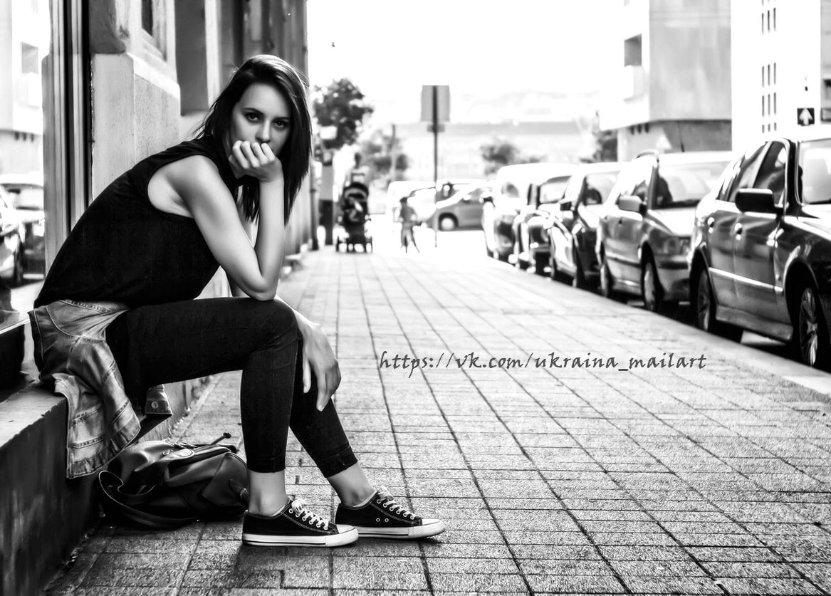 Schwarz-weißes Foto einer jungen Frau, die nachdenklich auf einer Treppenstufe sitzt