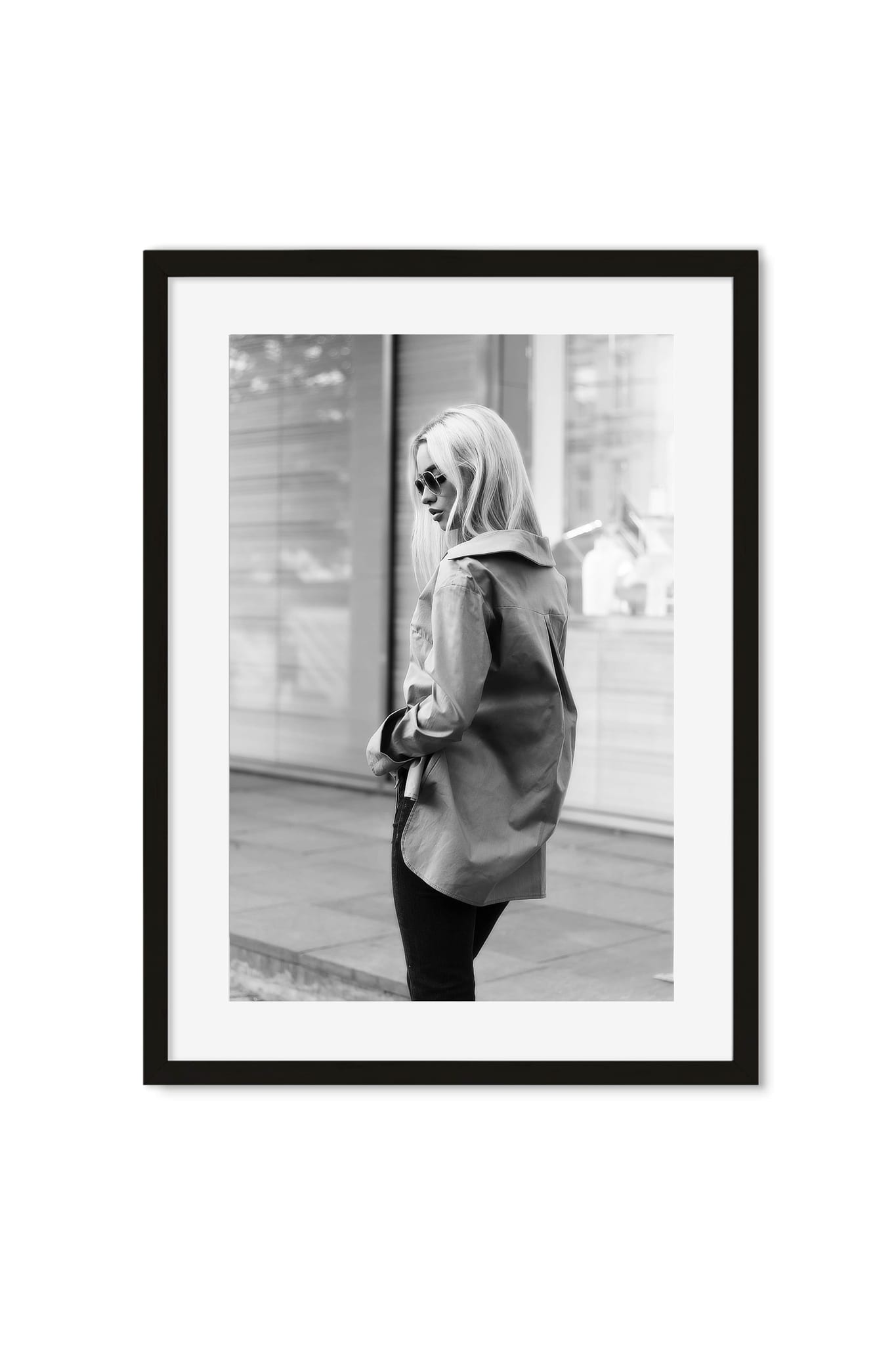 Black-and-white street-style photo of a woman in an oversized trench coat glancing back on a city street