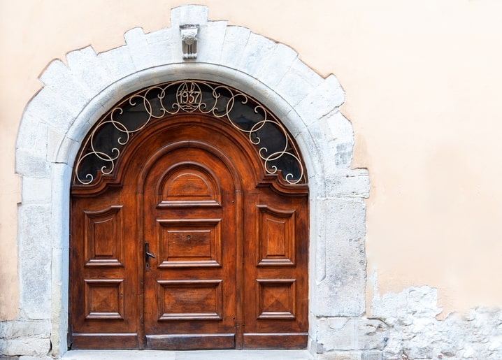 Carved wooden double door with an arched wrought-iron transom dated 1937 in Lviv