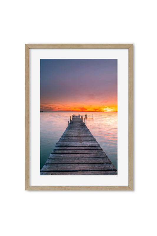 Photography poster of a wooden pier reaching into the water under an orange sunset