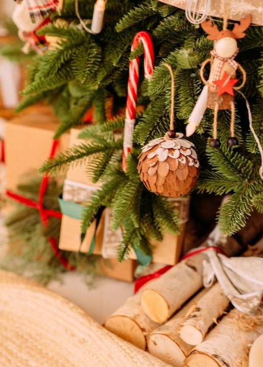 Nahaufnahme eines hölzernen Rentiers und Zapfen-Ornaments am Weihnachtsbaum
