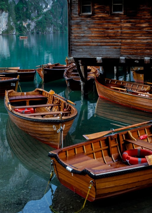 Wooden rowboats moored at a boathouse dock on a turquoise alpine lake