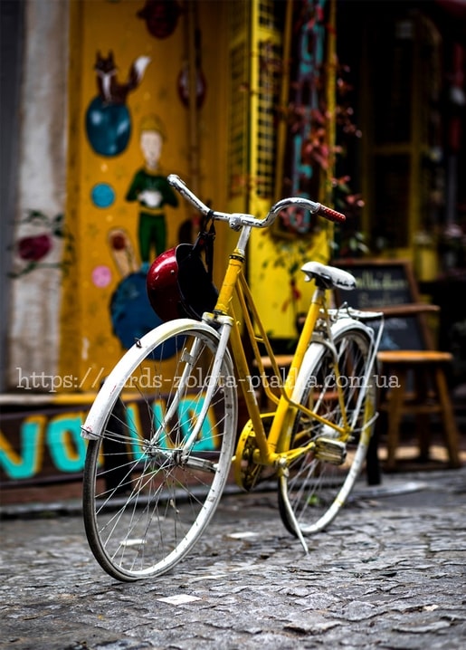 Yellow vintage bicycle with a red helmet parked in front of a Little Prince mural