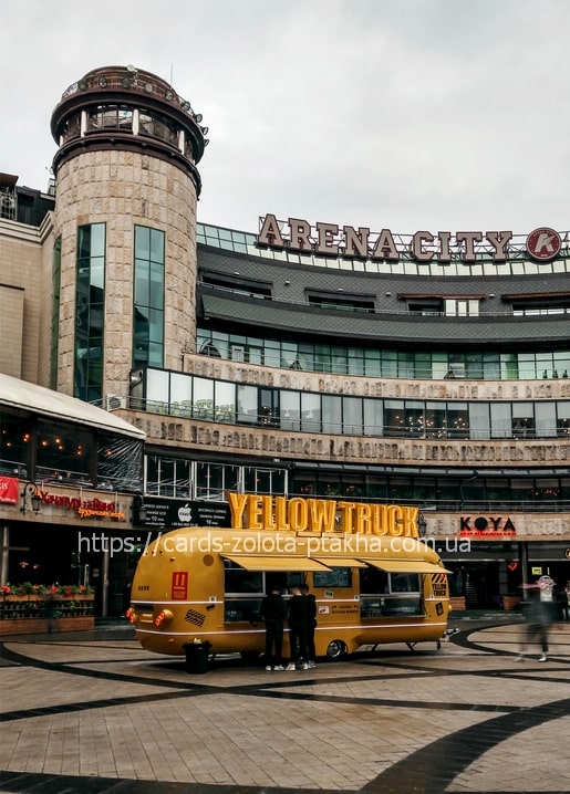 Gelber Foodtruck Yellow Truck vor dem Einkaufszentrum Arena City in Kiew mit Menschen daneben